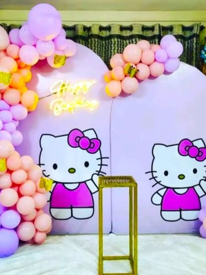 Another take on the popular Hello Kitty theme, using custom arched backdrops with character graphics. The decoration is completed with a 'Happy Birthday' neon sign and a pastel balloon garland.