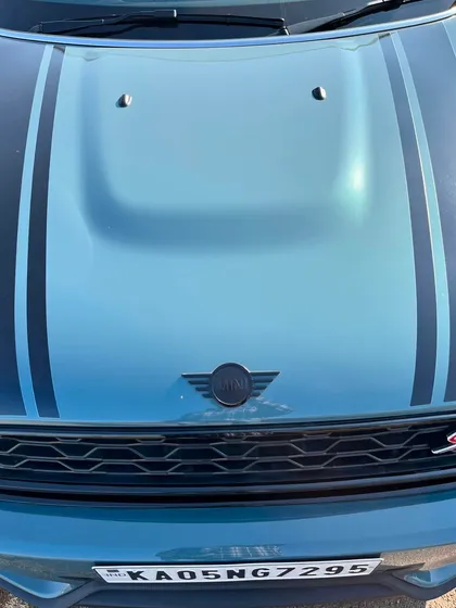 A close-up on the hood and emblem of a Mini, highlighting the racing stripes.