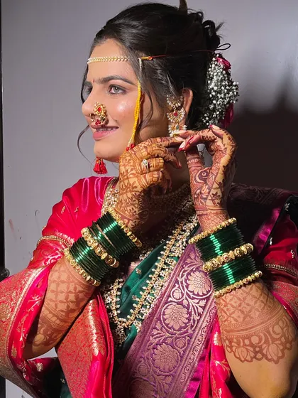 A candid moment of the bride adjusting her earrings. The detailed henna and green bangles are an integral part of the look.