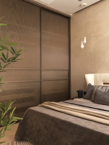 Fluted glass wardrobe doors add texture and a touch of modern elegance to this bedroom, while the pendant lights cast a warm, inviting glow over the layered bedding.