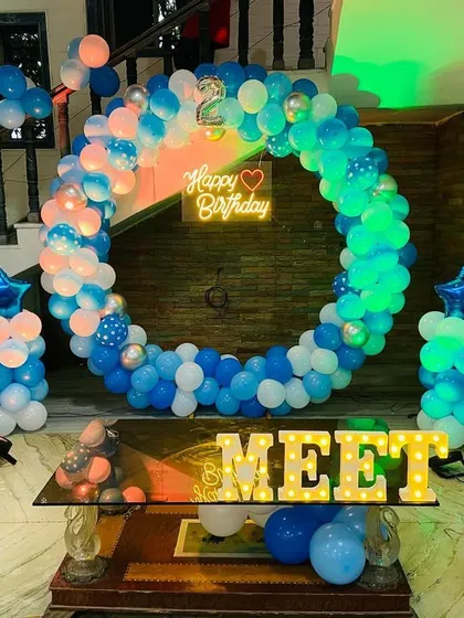 A Doraemon-themed birthday party setup for a second birthday. The decor features a circular balloon arch in shades of blue and character cutouts.