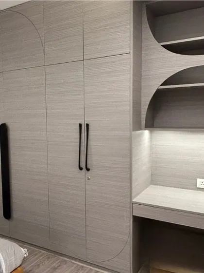 This monochrome unit combines a wardrobe and a study desk. The curved geometric patterns routed into the laminate add a subtle design detail, unifying the two functional zones into one cohesive piece of furniture.