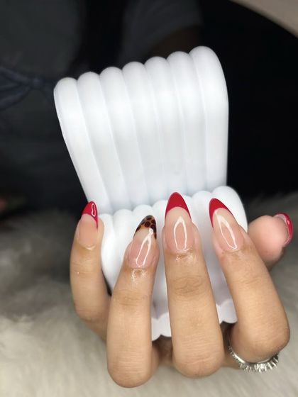 A side view of the tortoise shell and red French tip manicure, highlighting the glossy finish and sharp shape of the extensions.