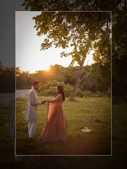 A wide shot of the couple in a sun-drenched field, capturing the beautiful light and natural setting of their outdoor shoot.