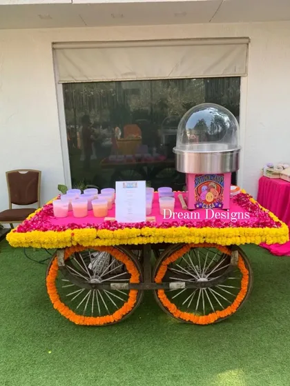 A fun and whimsical addition to a Mehndi celebration. This traditional cart, decorated with marigold and fuschia flowers, serves cotton candy, adding a playful and sweet touch for guests.