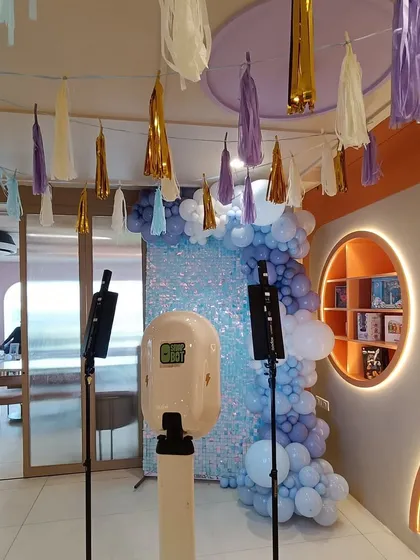 A view of a party setup that includes a photo booth against a blue shimmer wall. This shows that we can provide interactive elements like photo booths to complement our decor and enhance the guest experience.