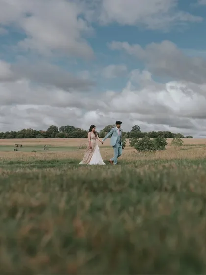 A romantic walk through a field under a dramatic sky. This shot from a UK wedding captures the feeling of a classic love story, blending nature with romance.