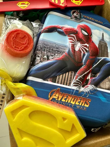 A superhero gift box packed with a Spiderman pencil case, Superman and Iron Man soaps, and a slap-band rakhi.