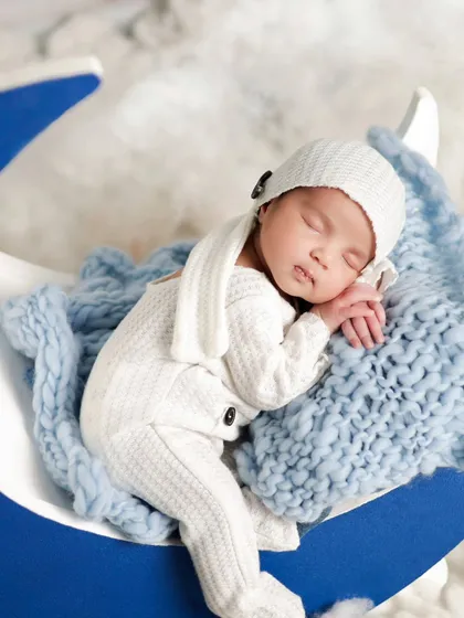 A close-up of a newborn sleeping on our moon prop. The soft white outfit and fluffy clouds create a dreamy, heavenly feel for the portrait.