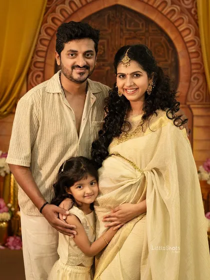 A beautiful family portrait from a traditionally themed maternity shoot. The rich golden tones of the backdrop and coordinated outfits create a regal and warm atmosphere.