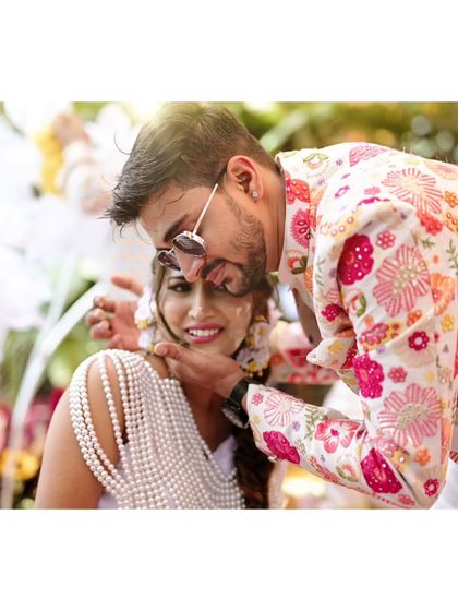 A cool groom in sunglasses shares a fun moment with his bride during their vibrant Haldi ceremony.
