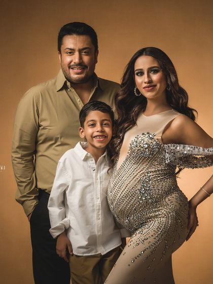 A striking family portrait with a fine art feel. The rich, warm tones and elegant attire make this a truly gallery-worthy maternity photograph.