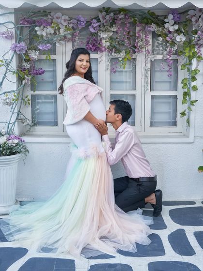 A partner's loving kiss on the baby bump. This photo shows our unique rainbow pastel gown, a sweet and colorful choice for celebrating your rainbow baby.