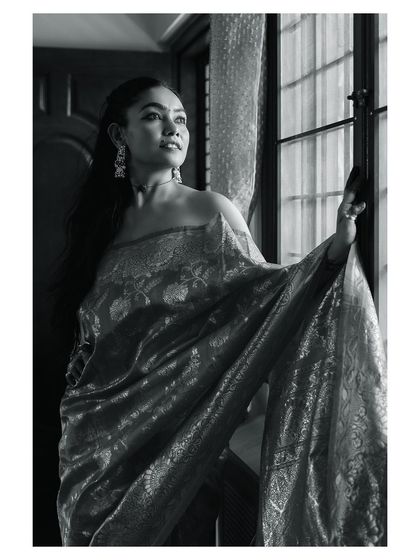 The same scene in timeless black and white. This version emphasizes the play of light and shadow, the textures of the saree, and the model's contemplative mood, creating a classic, artistic portrait.