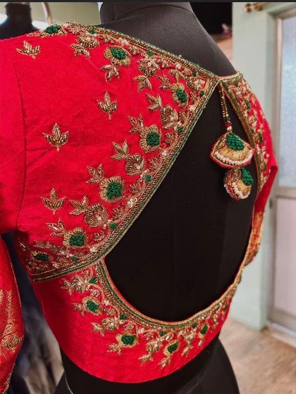 A side view of the red open-back blouse, showing the delicate tassels and the floral embroidery along the back.