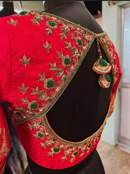 A side view of the red open-back blouse, showing the delicate tassels and the floral embroidery along the back.