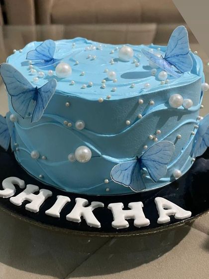This beautiful cake features a dreamy blue wave frosting design, adorned with delicate blue butterflies and white pearls. It's a serene and elegant option that's very popular on Pinterest and Instagram.