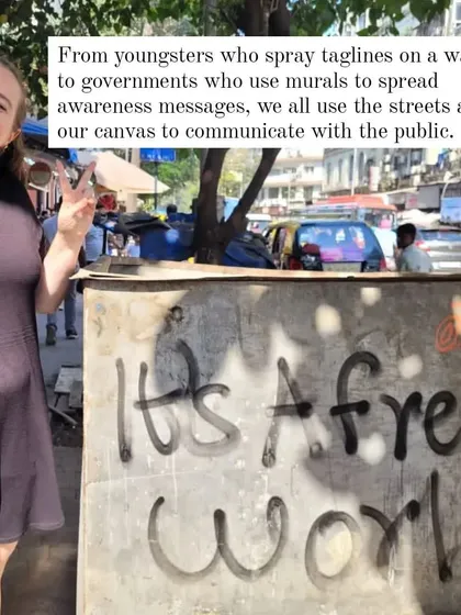 "It's A Free World." A simple but powerful message sprayed on a utility box. This image, featuring a smiling visitor, captures the democratic nature of street art as a canvas for public communication.