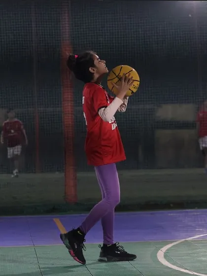 The same young girl now in shooting position, demonstrating the progression from dribbling to scoring. It's about building a complete skill set.