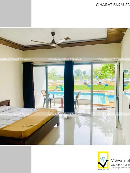 The interior of one of the rooms at Gharat Farm Stay. The design is simple, clean, and functional, with a large sliding door that opens directly to a patio with a pool view.