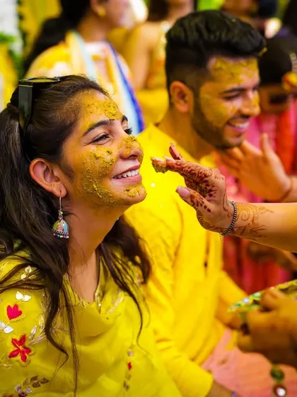 A friend applies haldi to the bride's face, a classic and essential shot from any haldi ceremony.