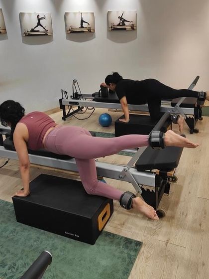 A perfect snapshot of a reformer session in progress. The focus here is on controlled leg work using ankle weights and the box, which helps to isolate and strengthen the glutes and hamstrings.