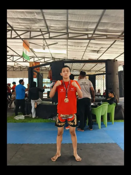 One of our young champions with his gold medal at the RAW Championship 2.0, standing proudly in front of the cage.
