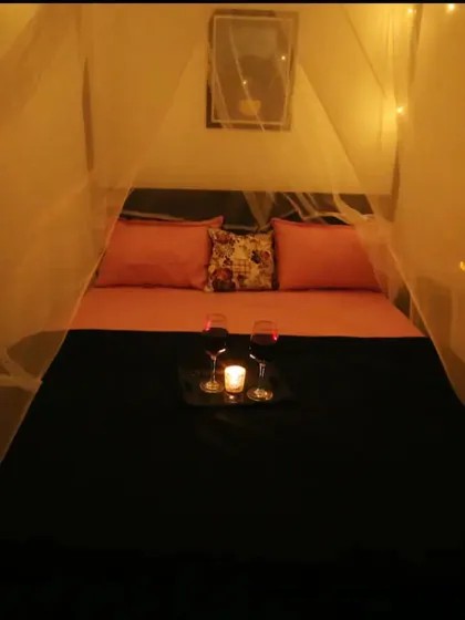 A straight-on view of the cabana bed setup, showing the cozy pink and black bedding and the intimate lighting.