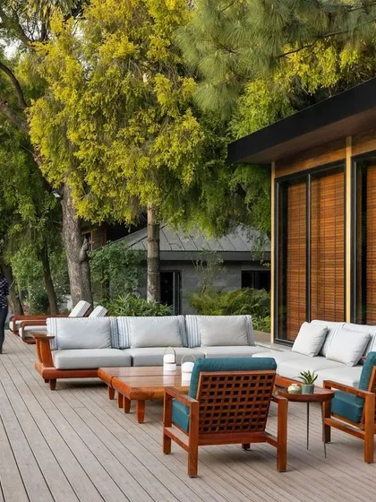 The spacious wooden deck provides ample room for multiple seating arrangements, including a large outdoor sofa. The design encourages a relaxed, resort-like lifestyle.