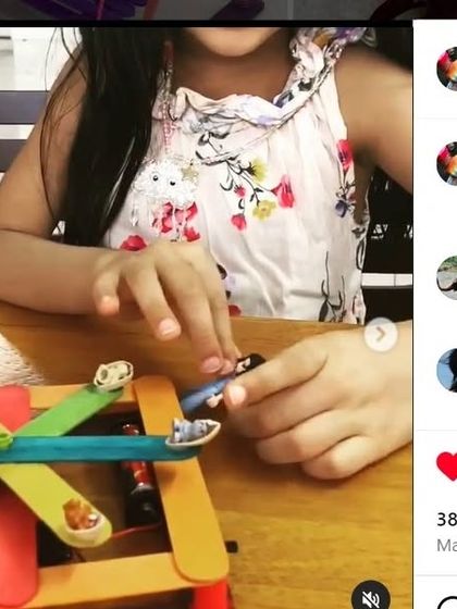 A child plays with a toy ferris wheel made from popsicle sticks, a great example of DIY making. Our workshops spark creativity and show kids how to build and invent using simple materials.