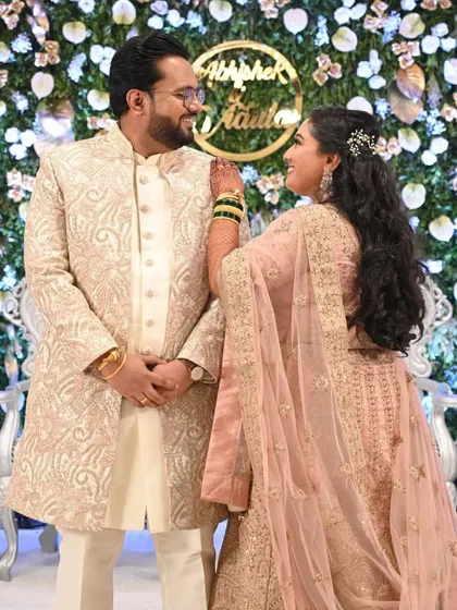 A happy couple at their reception. The bride's pastel pink lehenga is a modern and chic choice, paired with a soft, romantic makeup look.