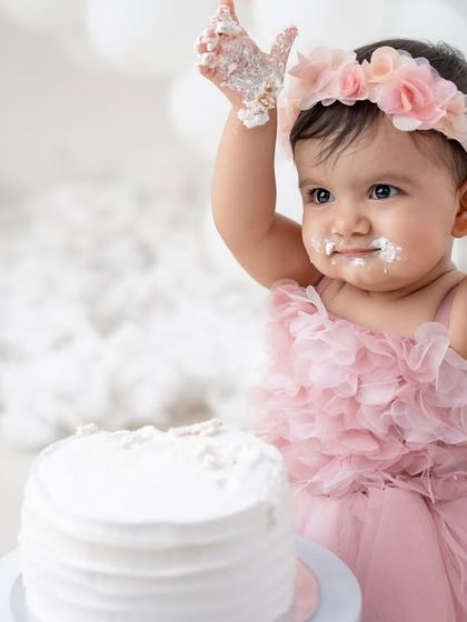 "All done!" A baby girl with frosting on her hands and face after a very successful cake smash.