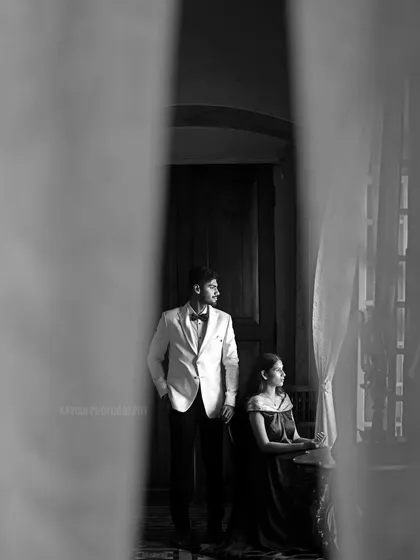 A creative composition, shooting through a curtain to frame the couple in a soft, ethereal way.