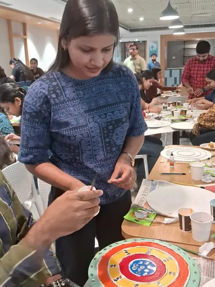 An instructor helps a participant during a corporate Lippan art workshop. We ensure a supportive and engaging experience for everyone, regardless of their artistic background.