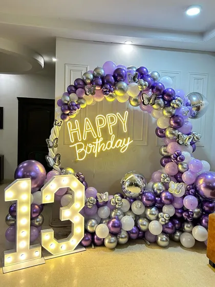 A different angle of the chic 13th birthday home decoration. The full balloon arch and large light-up numbers create a fantastic focal point for the celebration.