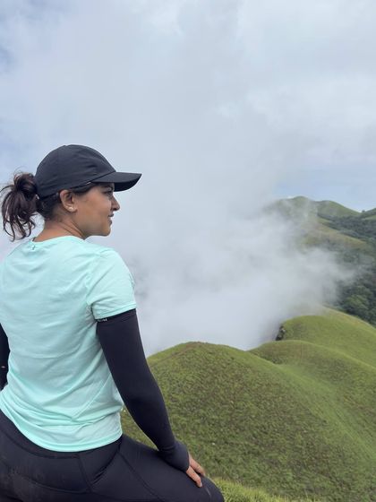A trekker looks out over the misty green hills of Netravathi, a perfect moment of quiet contemplation.