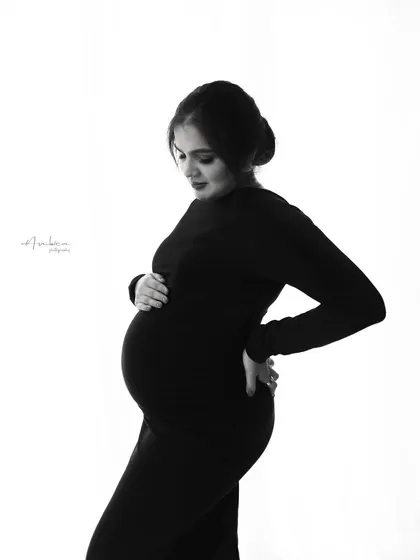 This high-contrast monochrome portrait emphasizes the beautiful silhouette of pregnancy. The pose, with her hand on her back, is both natural and flattering, creating a simple yet powerful image.