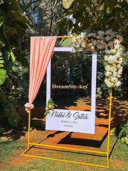 A chic and modern welcome sign for a wedding, framed with soft draping and fresh flowers. It's a beautiful first impression for your guests.