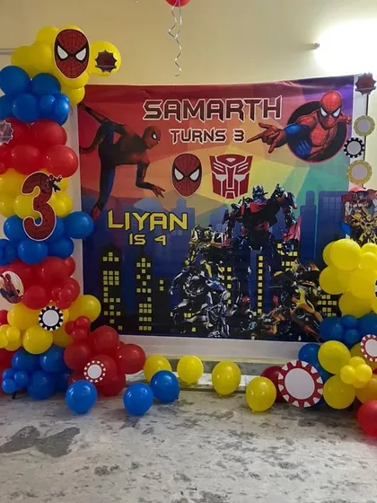 A joint birthday party setup featuring both Spider-Man and Transformers. The backdrop and balloon columns are customized to celebrate two different themes together.