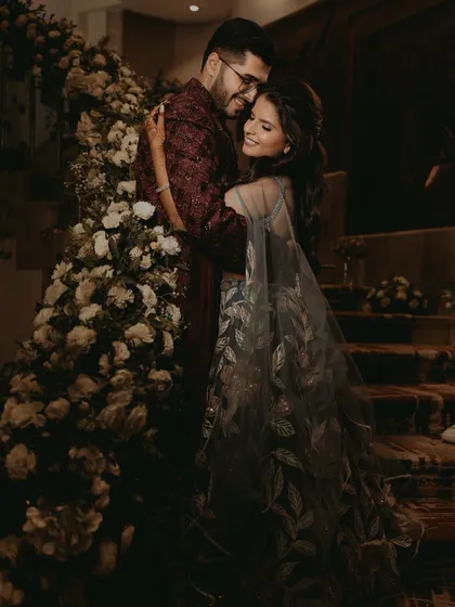 A romantic embrace between the couple on their Sangeet night, surrounded by elegant floral decorations.