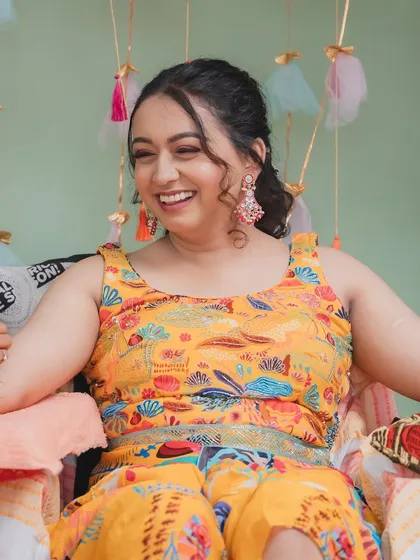 A joyful, laughing shot of the bride at her Mehendi. The vibrant yellow outfit is perfectly complemented by the all-pink makeup look, creating a fun and festive style.