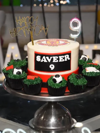 Celebrate your favorite football club with a custom cake. This Manchester United themed cake comes with matching football cupcakes, making it a perfect set for a sports fan's birthday party.