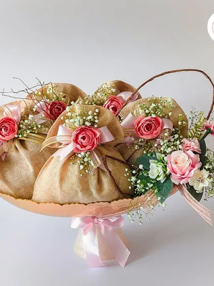 For a more rustic or eco-chic wedding theme, I design charming arrangements like this one. It features individual jute potlis, filled with treats for guests, presented in a beautiful hand-finished basket adorned with soft pink florals.