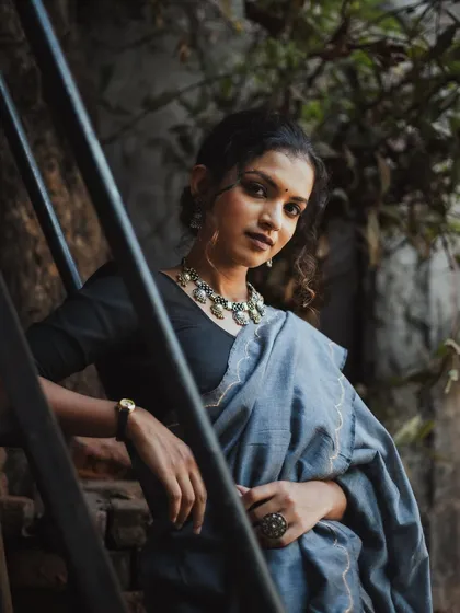 An angled shot looking up at the model, who is leaning against a dark staircase. Her direct gaze and the dramatic lighting create a powerful and confident portrait.