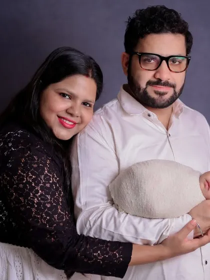 A happy studio portrait of new parents with their baby. The father holds the baby securely while the mother leans in, creating a composition that feels both posed and natural.