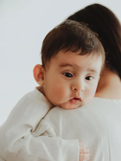 A close-up of a baby peeking over their mother's shoulder. These simple, quiet moments often make for the most compelling portraits.