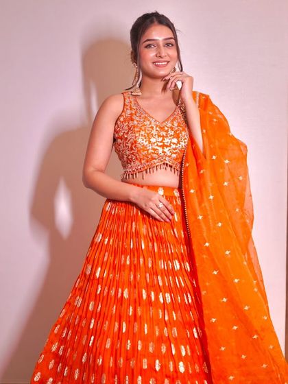 This bright orange lehenga with a pleated skirt and embellished blouse is a perfect blend of tradition and modernity.