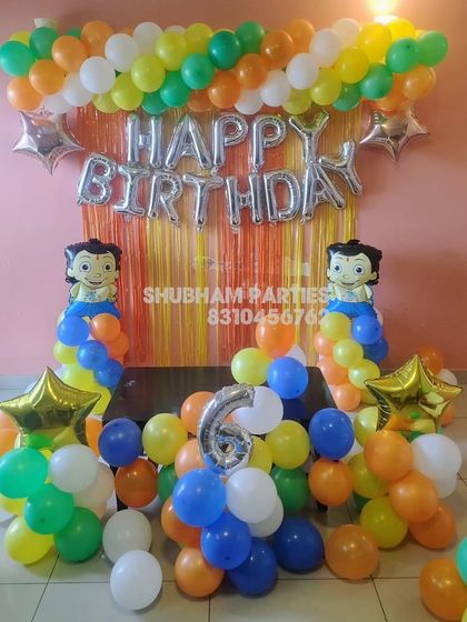 A Chhota Bheem themed birthday decoration with a colorful balloon and fringe backdrop.