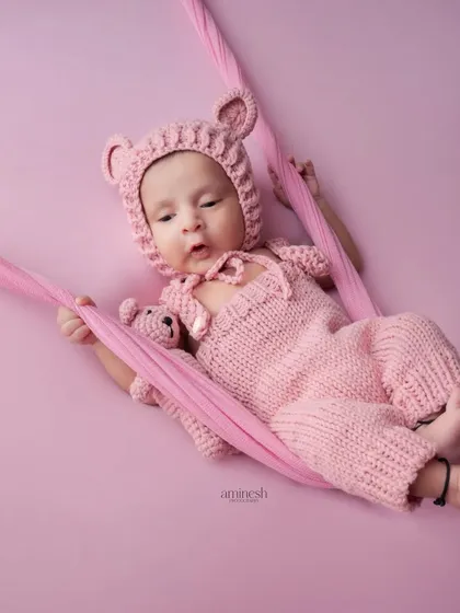 The color version of the previous portrait, this image shows the 20-day-old baby in a soft pink knitted outfit. The monochromatic color scheme creates a gentle and dreamy feel.