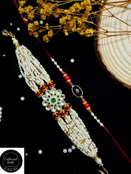 A grand, multi-layered pearl Lumba rakhi with a floral kundan centerpiece. This statement piece is paired with a simple, elegant rakhi for the brother.